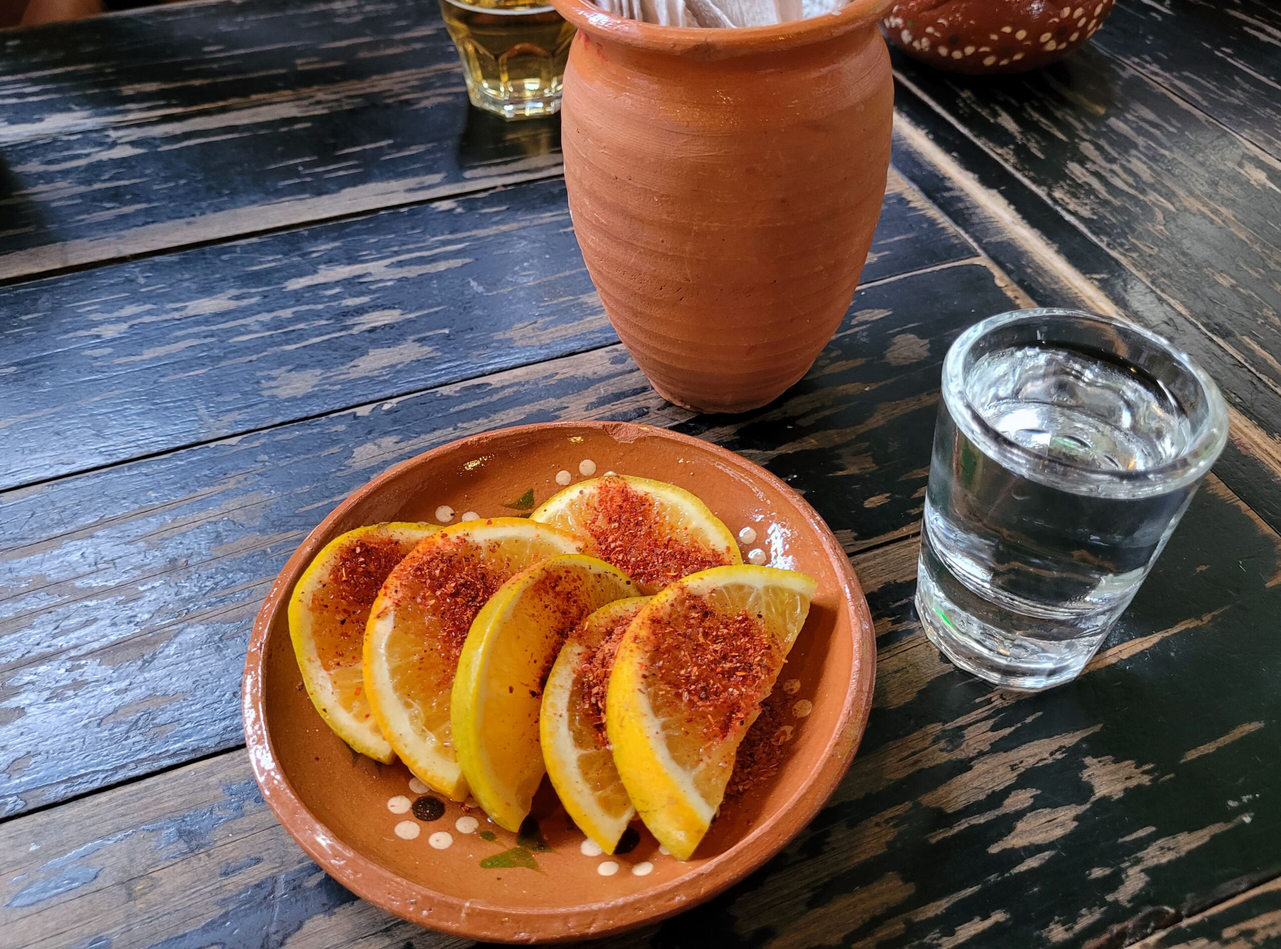 image of a small glass of mezcal with a plate of orange slices with chili powder 255000635 min scaled